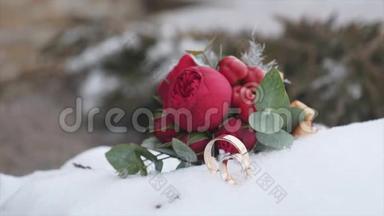 婚礼花束与结婚戒指与红色的花朵背景雪